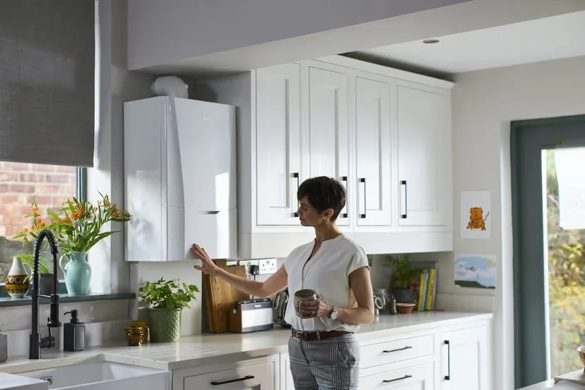 Homeowner adjusting a wall-mounted gas boiler in a kitchen